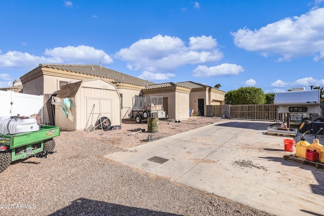 back of house with a storage shed and a patio area