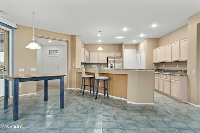 kitchen featuring a kitchen island, stainless steel refrigerator with ice dispenser, a kitchen bar, hanging light fixtures, and light stone counters