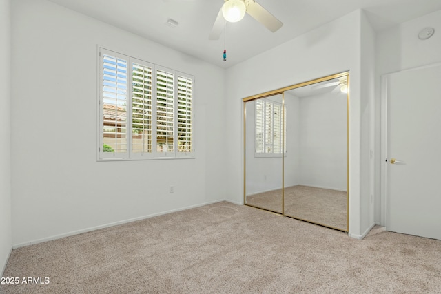 unfurnished bedroom featuring ceiling fan, light colored carpet, and a closet