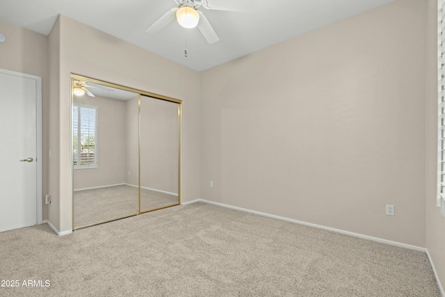 unfurnished bedroom featuring ceiling fan, a closet, and light carpet