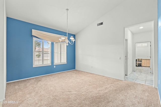 carpeted spare room with a chandelier and vaulted ceiling