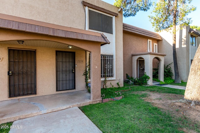 7126 N 19th Ave Unit 228, Phoenix, AZ 85021 - view of exterior entry featuring stucco siding and a yard