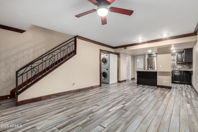 7126 N 19th Ave Unit 228, Phoenix, AZ 85021 - unfurnished living room featuring estacked washer and dryer, ornamental molding, light wood-style flooring, stairs, and a ceiling fan