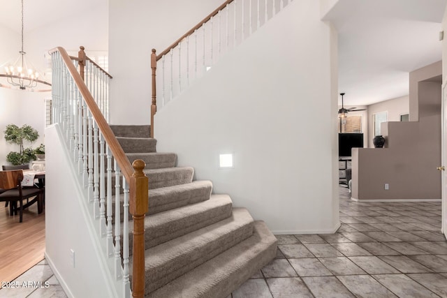 stairway featuring ceiling fan with notable chandelier and baseboards