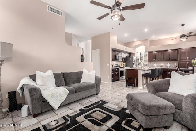 living room with ceiling fan, visible vents, baseboards, and light tile patterned flooring