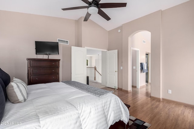 bedroom featuring high vaulted ceiling, visible vents, arched walkways, and wood finished floors