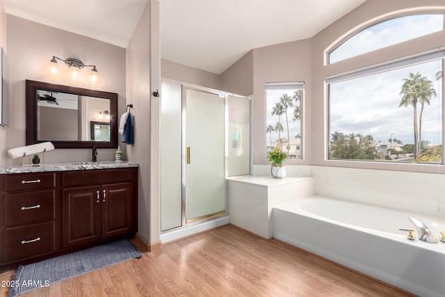 full bathroom featuring a bath, a shower stall, wood finished floors, and vanity