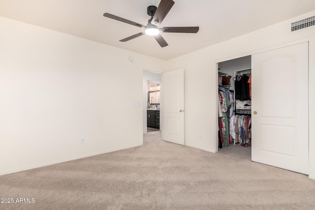 unfurnished bedroom featuring ceiling fan, light colored carpet, a closet, and a walk in closet