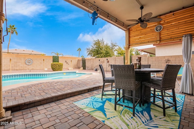 view of patio with a fenced backyard, a fenced in pool, a ceiling fan, and outdoor dining space