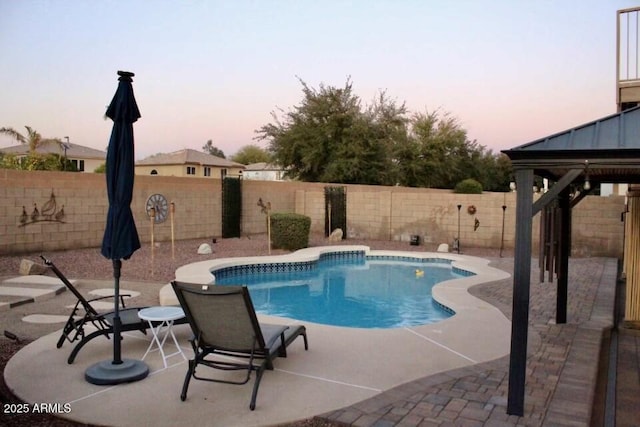 pool at dusk featuring a fenced in pool, a fenced backyard, and a patio