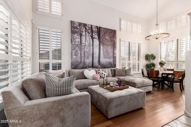 living room with a chandelier, high vaulted ceiling, and wood finished floors