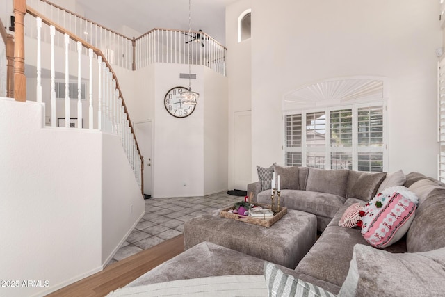 living room featuring an inviting chandelier, a towering ceiling, and light wood-type flooring