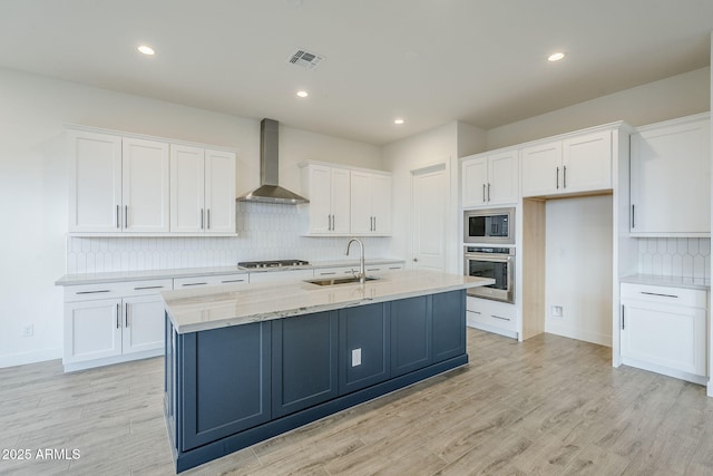 kitchen with oven, visible vents, a sink, wall chimney range hood, and built in microwave