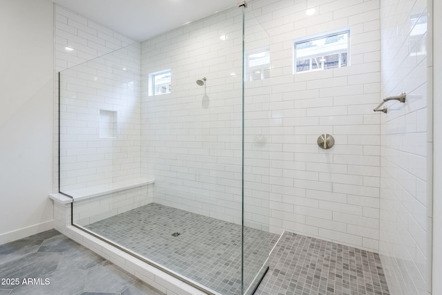 bathroom with a wealth of natural light, tiled shower, and baseboards