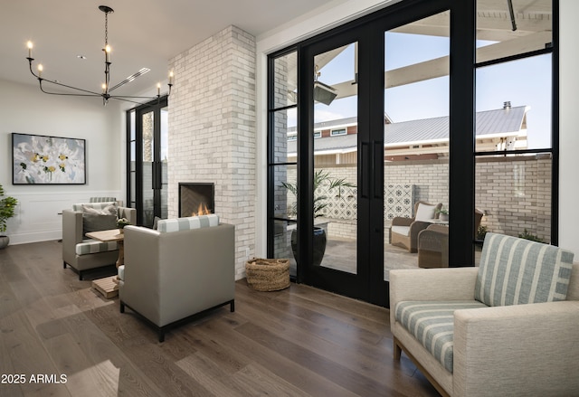 living room featuring a notable chandelier, a fireplace, a wall of windows, and wood finished floors