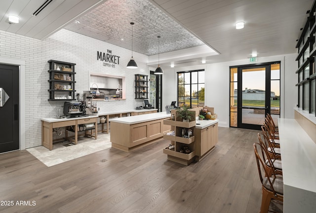 kitchen featuring light wood finished floors, brick wall, a center island, a raised ceiling, and open shelves