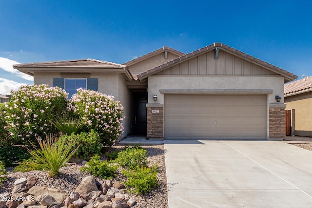 9822 W Caron Dr, Peoria, AZ 85345 - view of front of house featuring an attached garage, stone siding, a tiled roof, concrete driveway, and stucco siding