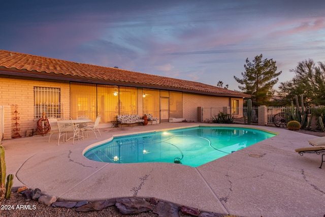 pool at dusk featuring a patio area