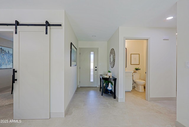 foyer featuring a barn door and baseboards