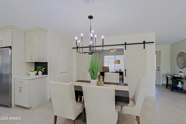 dining area featuring an inviting chandelier, a barn door, and baseboards