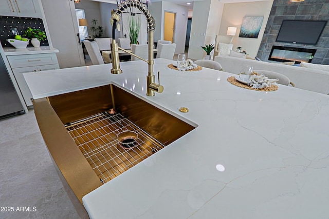 details featuring fridge, a tiled fireplace, and light stone countertops