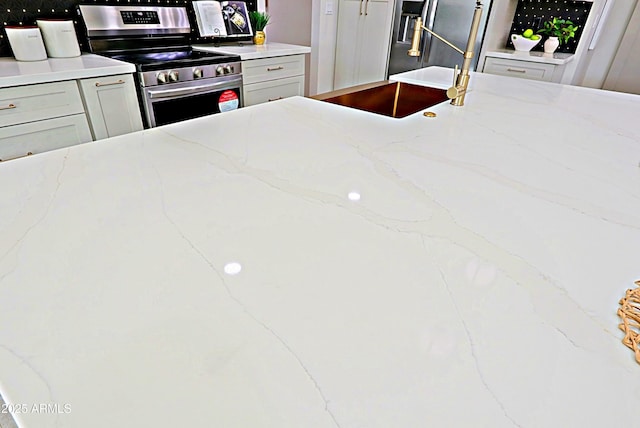 kitchen with stainless steel electric range oven, a sink, and light stone countertops