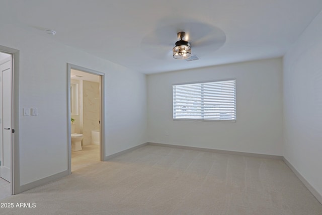 spare room featuring light colored carpet, ceiling fan, visible vents, and baseboards