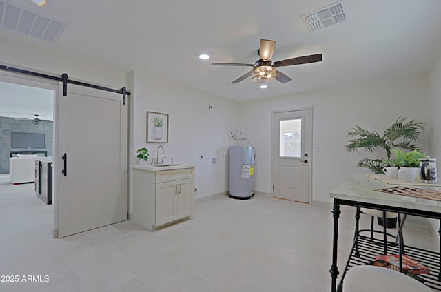 kitchen featuring a barn door, visible vents, a sink, and electric water heater