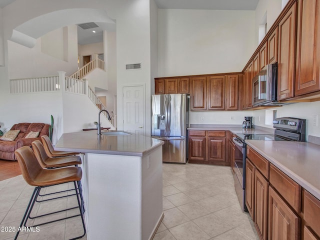 40814 N Majesty Ct, Anthem, AZ 85086 - kitchen featuring stainless steel appliances, a high ceiling, light tile patterned flooring, a kitchen bar, and brown cabinets