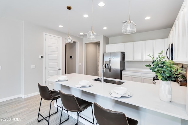 19958 W Turney Ave, Litchfield Park, AZ 85340 - kitchen featuring white cabinets, a peninsula, a breakfast bar, and appliances with stainless steel finishes