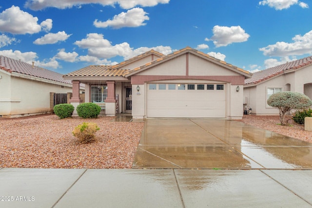 view of front of house with an attached garage, driveway, a tiled roof, and stucco siding