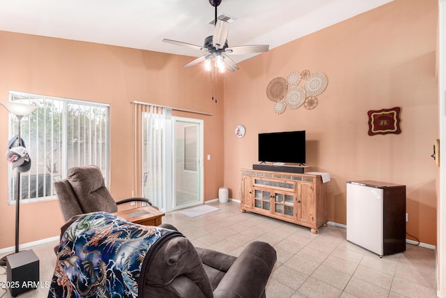 living area with light tile patterned floors, visible vents, baseboards, and a ceiling fan