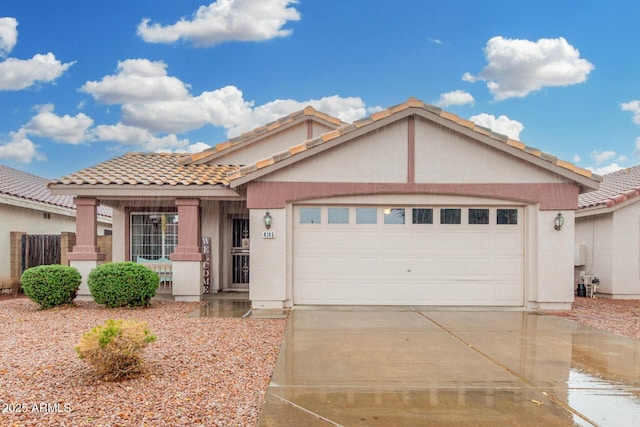 view of front of home with an attached garage, a tiled roof, concrete driveway, and stucco siding