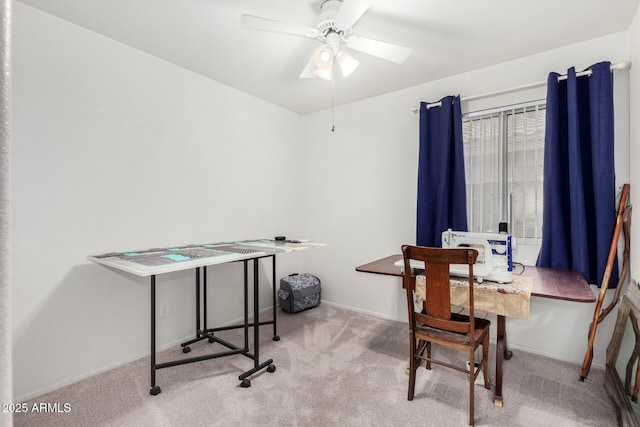 carpeted office space featuring ceiling fan and baseboards