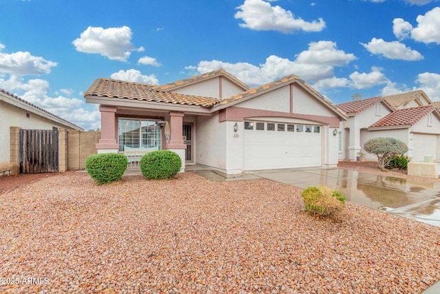 view of front of house featuring concrete driveway, a tile roof, an attached garage, a gate, and stucco siding