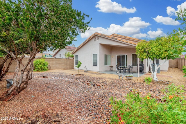 rear view of house with a patio, a tile roof, a fenced backyard, and stucco siding