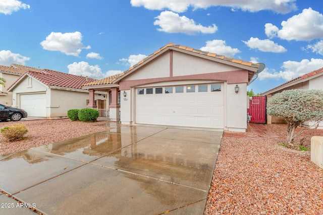 view of front of house with driveway, a tiled roof, an attached garage, and stucco siding