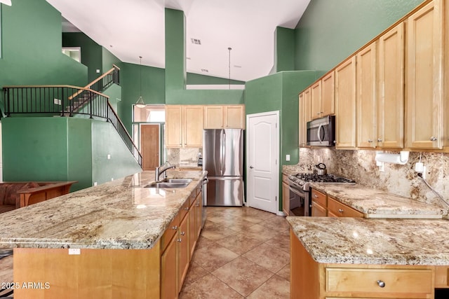 kitchen featuring light stone countertops, stainless steel appliances, a sink, decorative backsplash, and light brown cabinetry