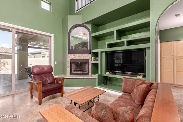 tiled living area featuring built in shelves, a tile fireplace, and a towering ceiling