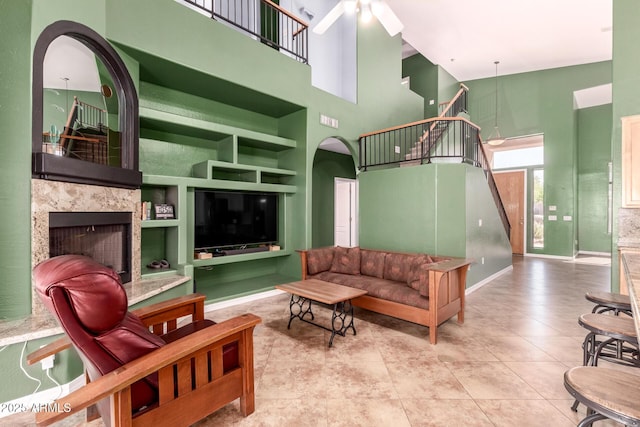 living room with arched walkways, a towering ceiling, built in features, stairway, and tile patterned floors