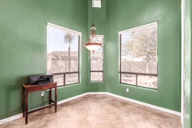 spare room with tile patterned flooring, plenty of natural light, and baseboards