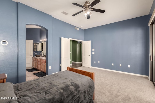 carpeted bedroom with arched walkways, visible vents, ceiling fan, a sink, and baseboards