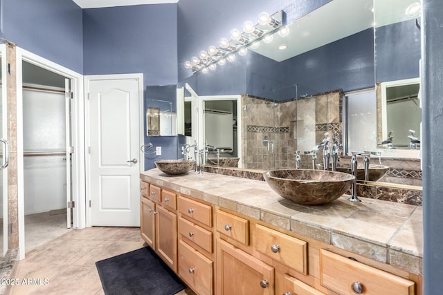 bathroom featuring double vanity, tile patterned floors, a sink, and tiled shower