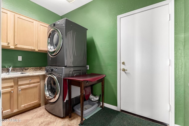 laundry room with stacked washer and dryer, cabinet space, a sink, and light tile patterned floors