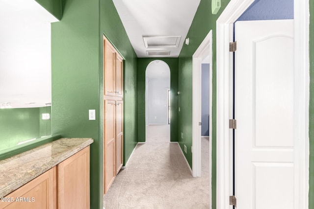 hall with light carpet, baseboards, and arched walkways