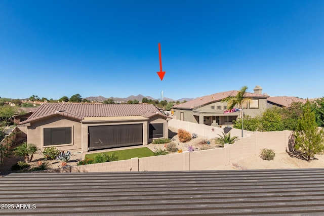 view of front of property with a garage, a fenced backyard, a tile roof, a mountain view, and stucco siding