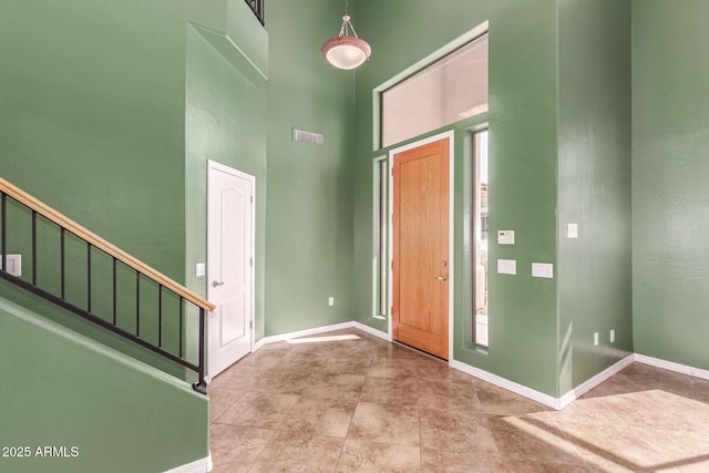 foyer entrance featuring visible vents, stairway, a towering ceiling, and baseboards