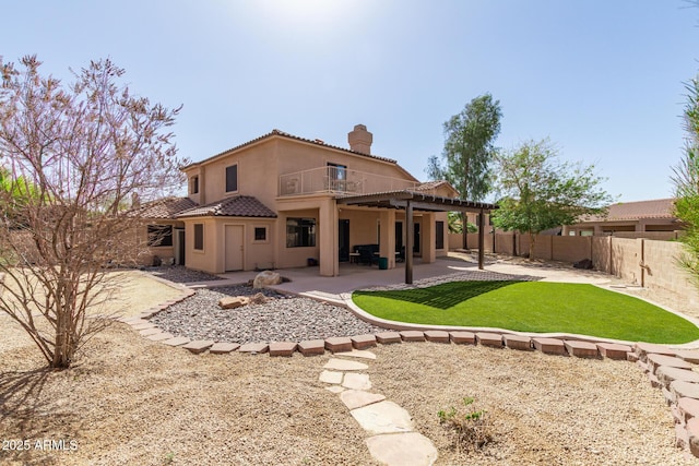 rear view of house with a chimney, stucco siding, a patio area, a fenced backyard, and a tiled roof