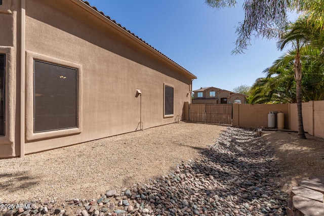 view of side of home with a patio, fence, and stucco siding