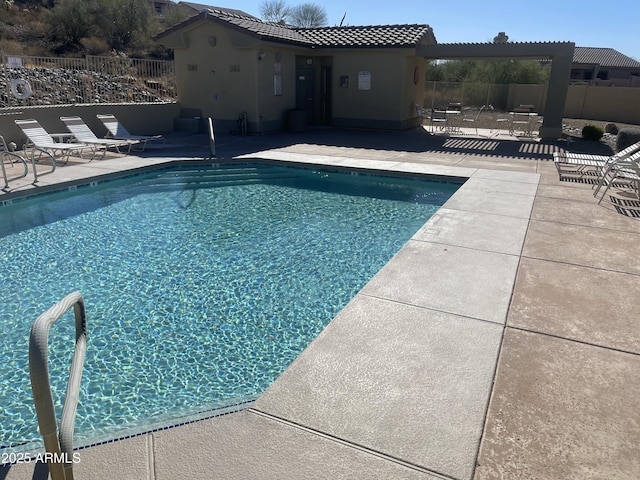 community pool with a patio area and fence